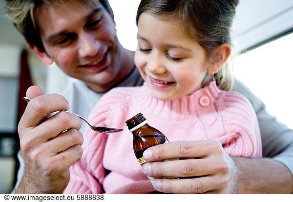 Close_up of a father giving syrup in a spoon to her daughter