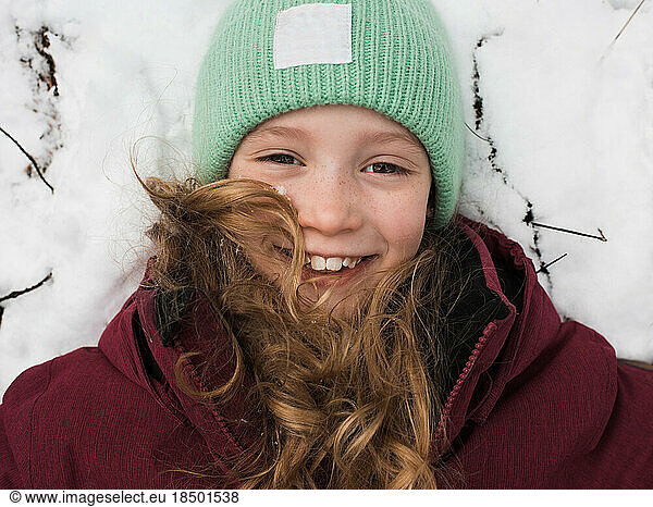 close up of a girl laying down in the snow smiling