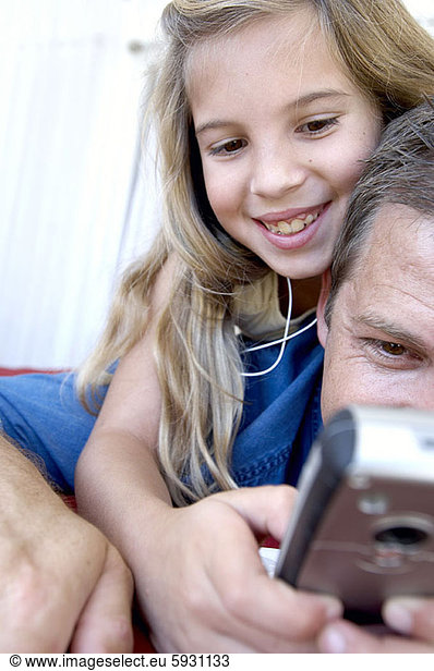 Close-up of a girl showing a mobile phone to her father. Close-up of a girl showing a mobile phone to her father