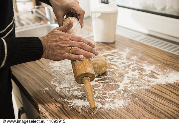 Close-up of a man applying flour on rolling pin