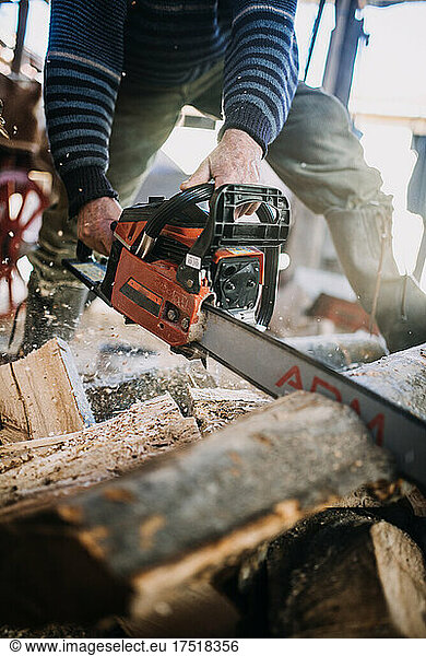Close-up of a man cutting wood with a chainsaw.