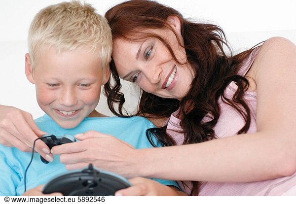 Close_up of a mid adult woman and her son playing a video game and smiling