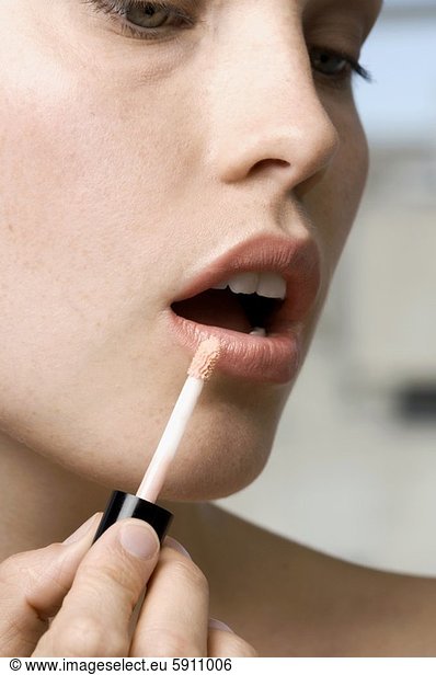 Close-up of a mid adult woman applying lipstick