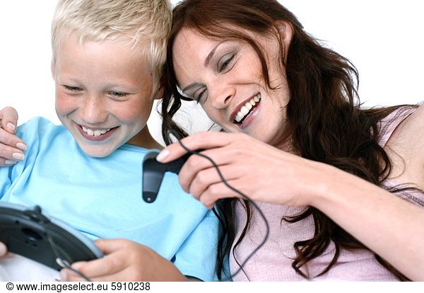 Close-up of a mid adult woman with her son playing video game with joysticks and smiling