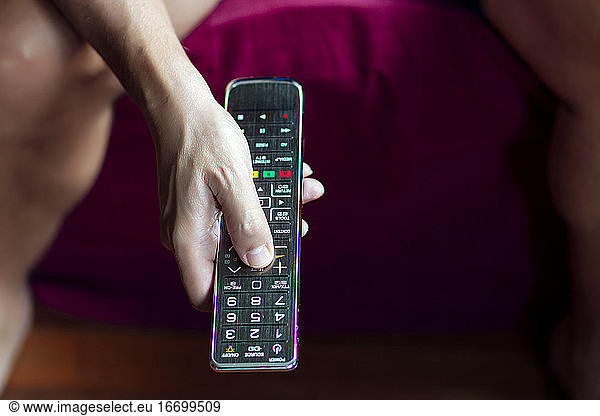 Close-up of a person changing the television with the remote control in quarantine period