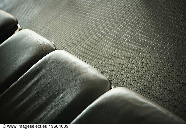 Close-up of a row of empty leather seat cushions and textured floor.