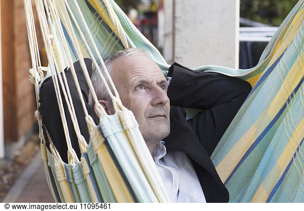 Close-up of a senior businessman lying on hammock and thinking  Freiburg im Breisgau  Baden-Württemberg  Germany