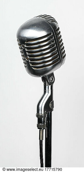 Close-up of a vintage  chrome studio microphone on a stand against a white background; Studio Shot
