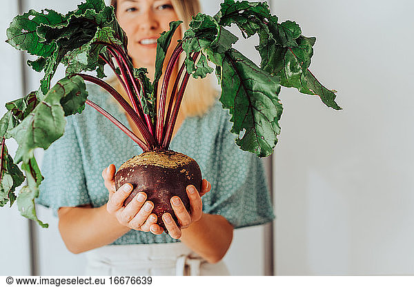 Close up of a woman holding a beetroot with leaves