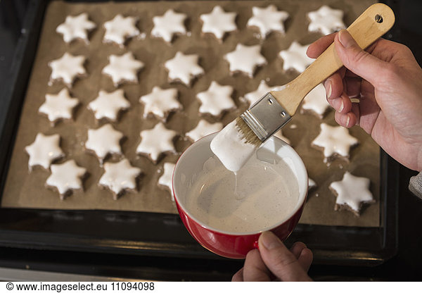Close-up of a woman icing star shape cinnamon with basting brush
