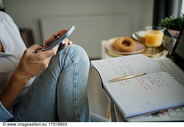 Close-up of a woman looking at her phone with a notebook and pen