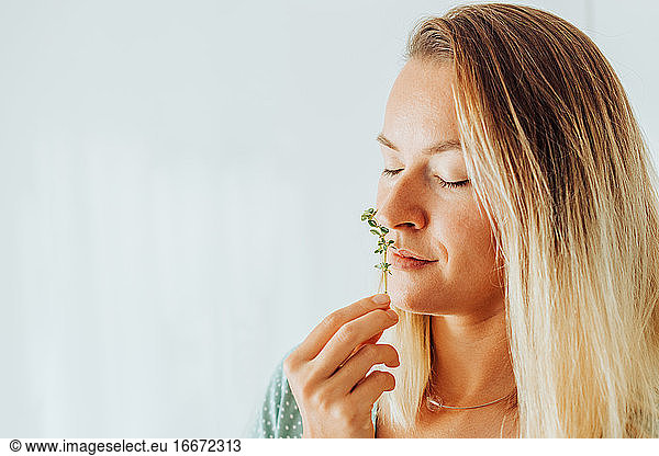 Close up of a woman smelling thyme  aromatic herbs on plain background