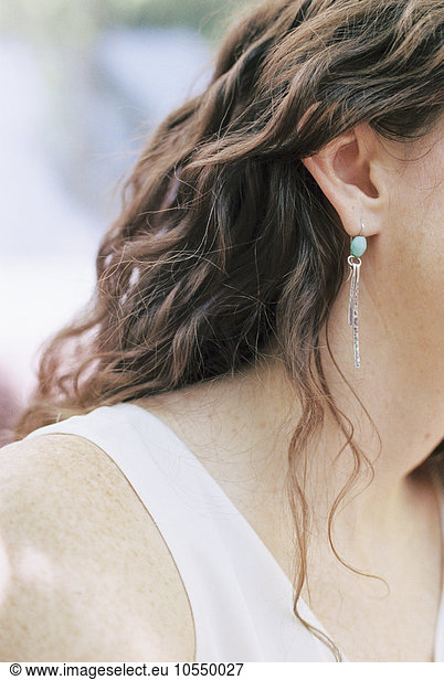 Close up of a woman wearing a silver and turquoise earring.