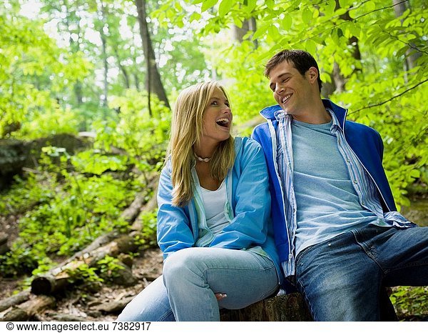 Close_up of a young couple sitting in the forest and smiling
