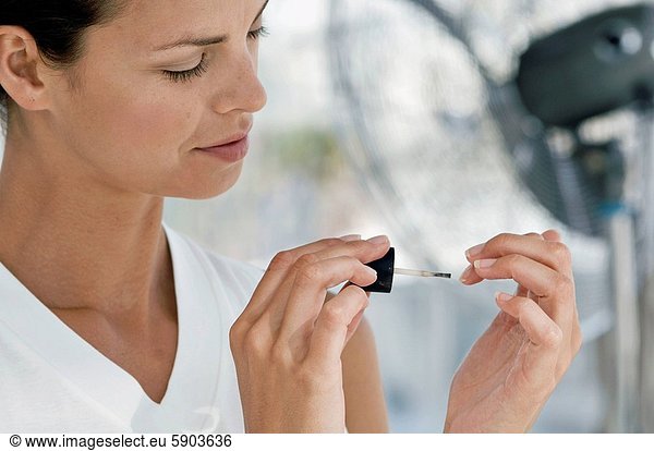 Close_up of a young woman painting her fingernails