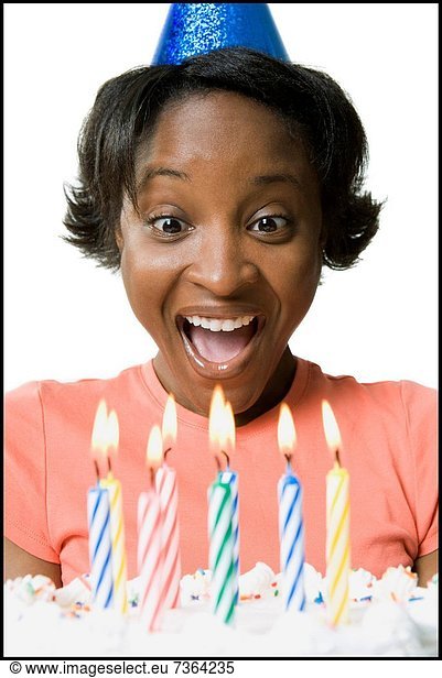 Close_up of a young woman smiling in front of a birthday cake