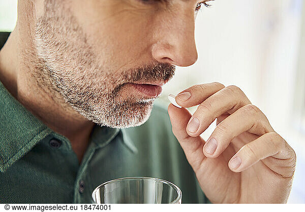 Close-up of adult man taking pill