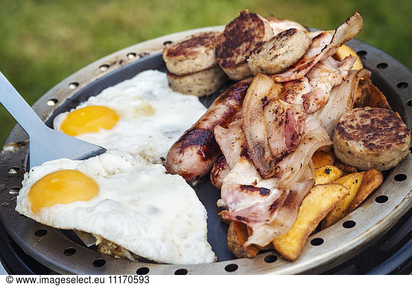 Close up of an English Breakfast fry up being prepared on a camping stove.
