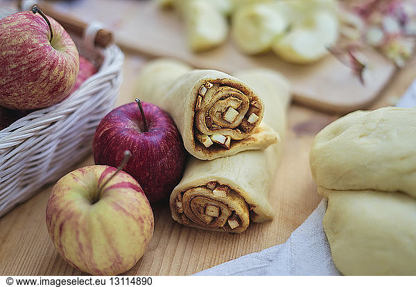 Close-up of apple slices and ground cinnamon rolled in pastry dough on kitchen counter