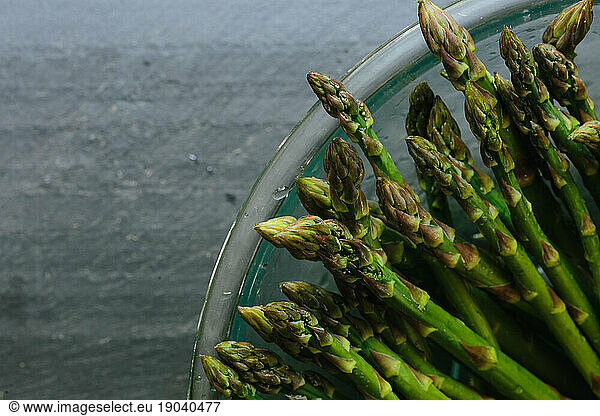 Close up of asparagus tips in bowl on slate countertop