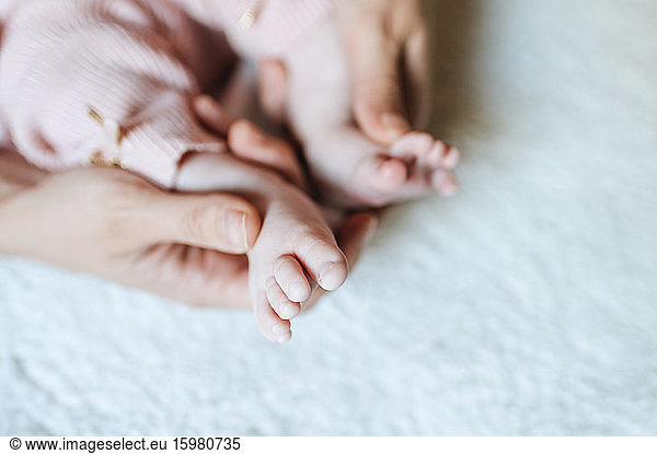Close-up of baby feet held by mother's hand