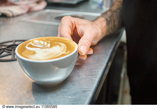 Close up of barista's hand and cup of coffee