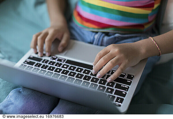 Close up of bi-racial tween girl's hands working on laptop