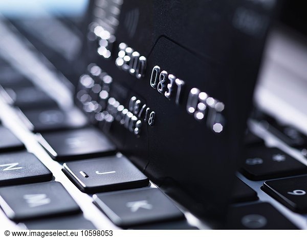 Close up of black credit card standing on computer keyboard