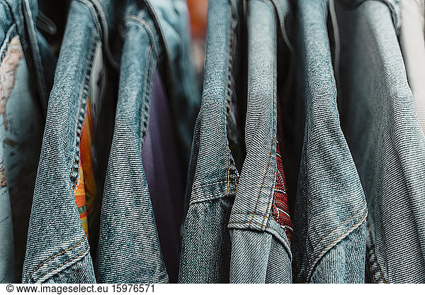 Close-up of blue denim jackets hanging on rack at clothing store