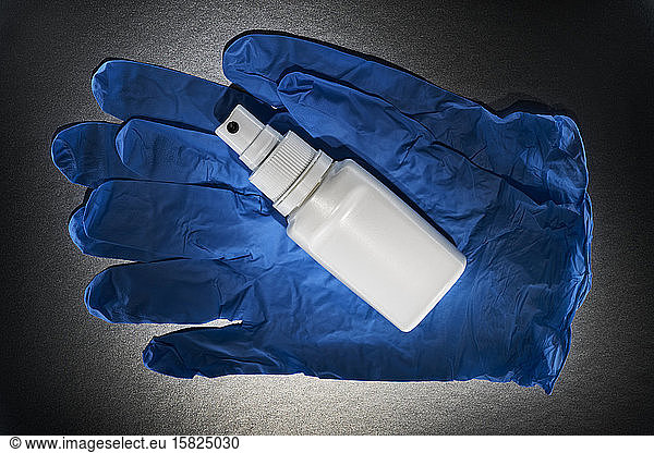 Close-up of blue surgical gloves and bottle of disinfectant spray
