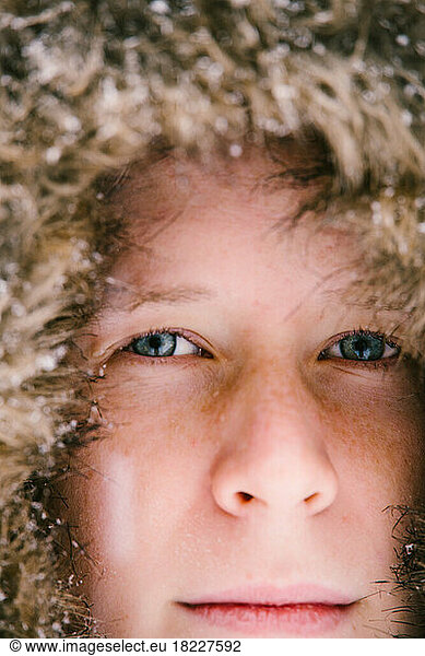 Close up of boy face with blue eyes  freckles and snowflakes on coat