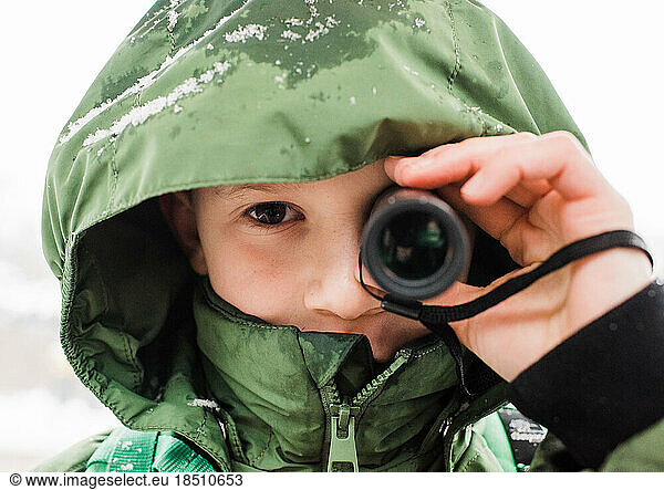 close up of boy looking through a telescope