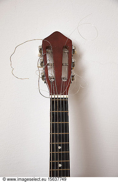 Close-up of broken guitar by white wall
