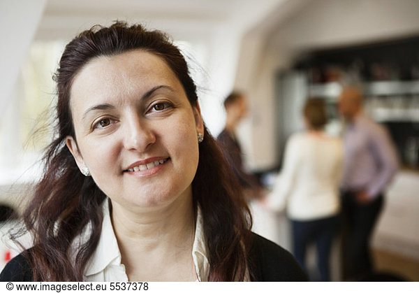 Close-up of business woman smiling with colleagues in background at work