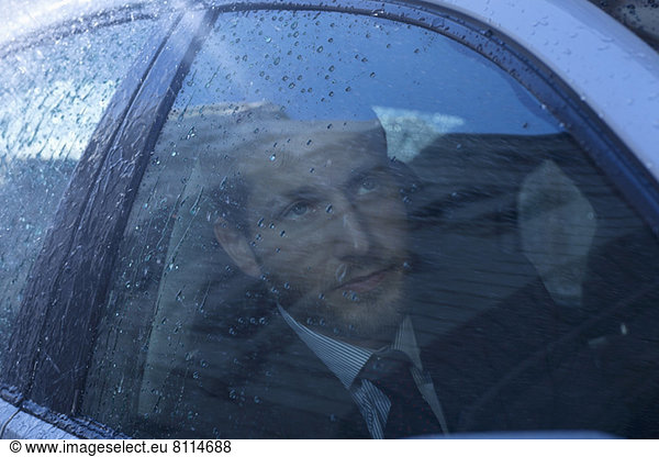 Close up of businessman in car looking up at rain