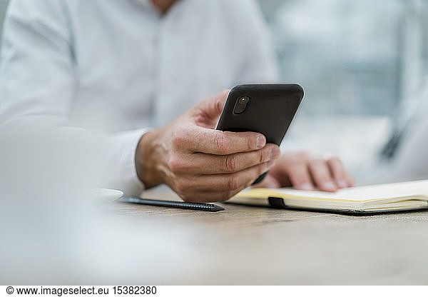 Close-up of businessman with notebook and cell phone