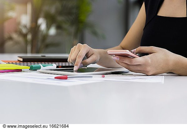 Close-up of businesswoman using digital tablet and smart phone on desk in office
