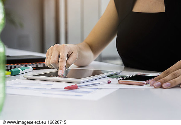 Close-up of businesswoman using digital tablet on desk in office