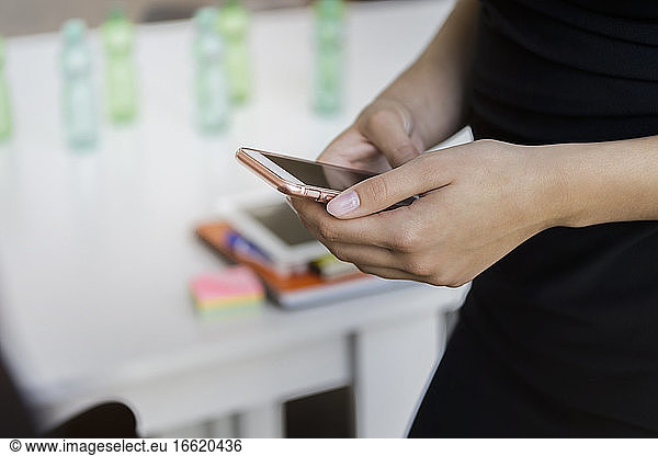 Close-up of businesswoman using smart phone while standing in office