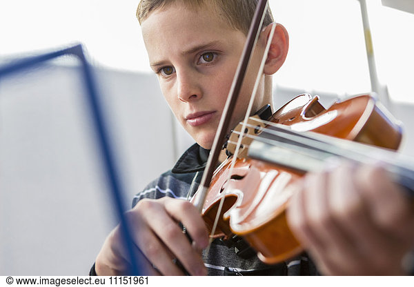 Close up of Caucasian boy playing violin