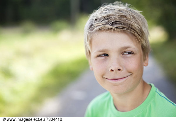 Close-up of Caucasian pre-adolescent boy smiling while looking sideways
