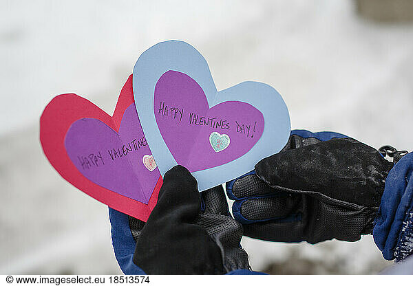 Close-up of child outside in winter holding Valentines day cards