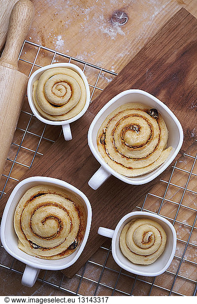 Close-up of cinnamon buns in cups on metal grate at kitchen counter