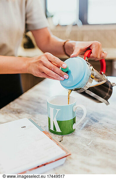 Close up of coffee being poured into cup from french press