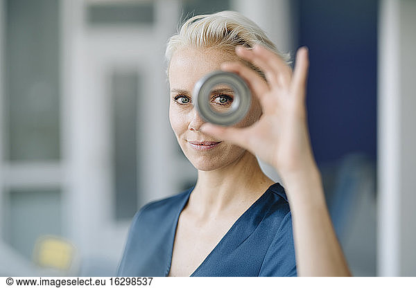 Close-up of confident businesswoman looking through object in office