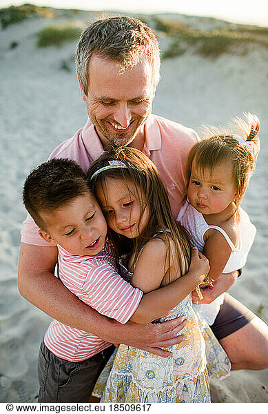 Close Up of Dad Holding His Three Children on Beach in San Diego