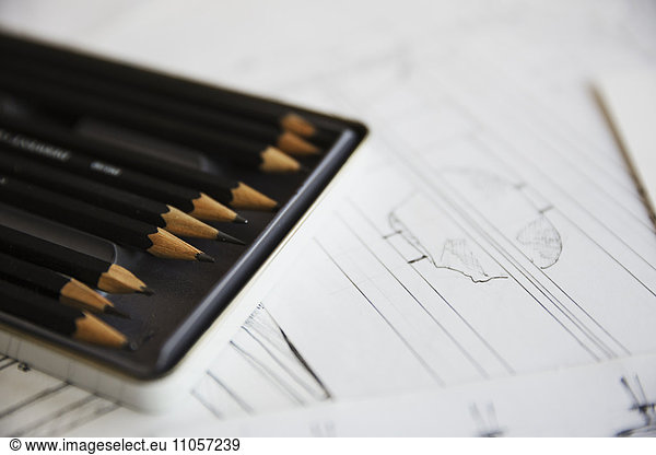 Close up of design drawings for furniture and a tray of pencils.