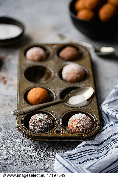 Close up of donut holes covered in sugar in a baking tin.