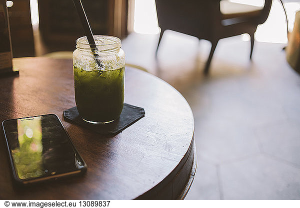 Close-up of drink by smart phone on table