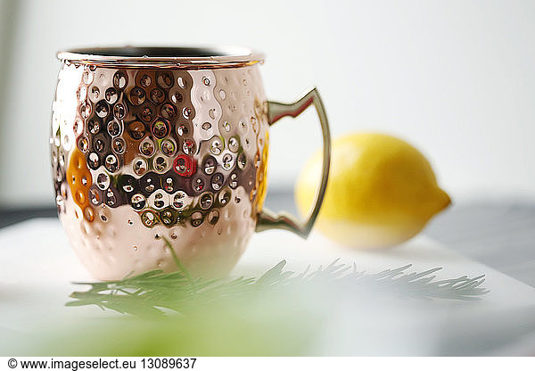 Close-up of drink in mug with lemon and rosemary in plate